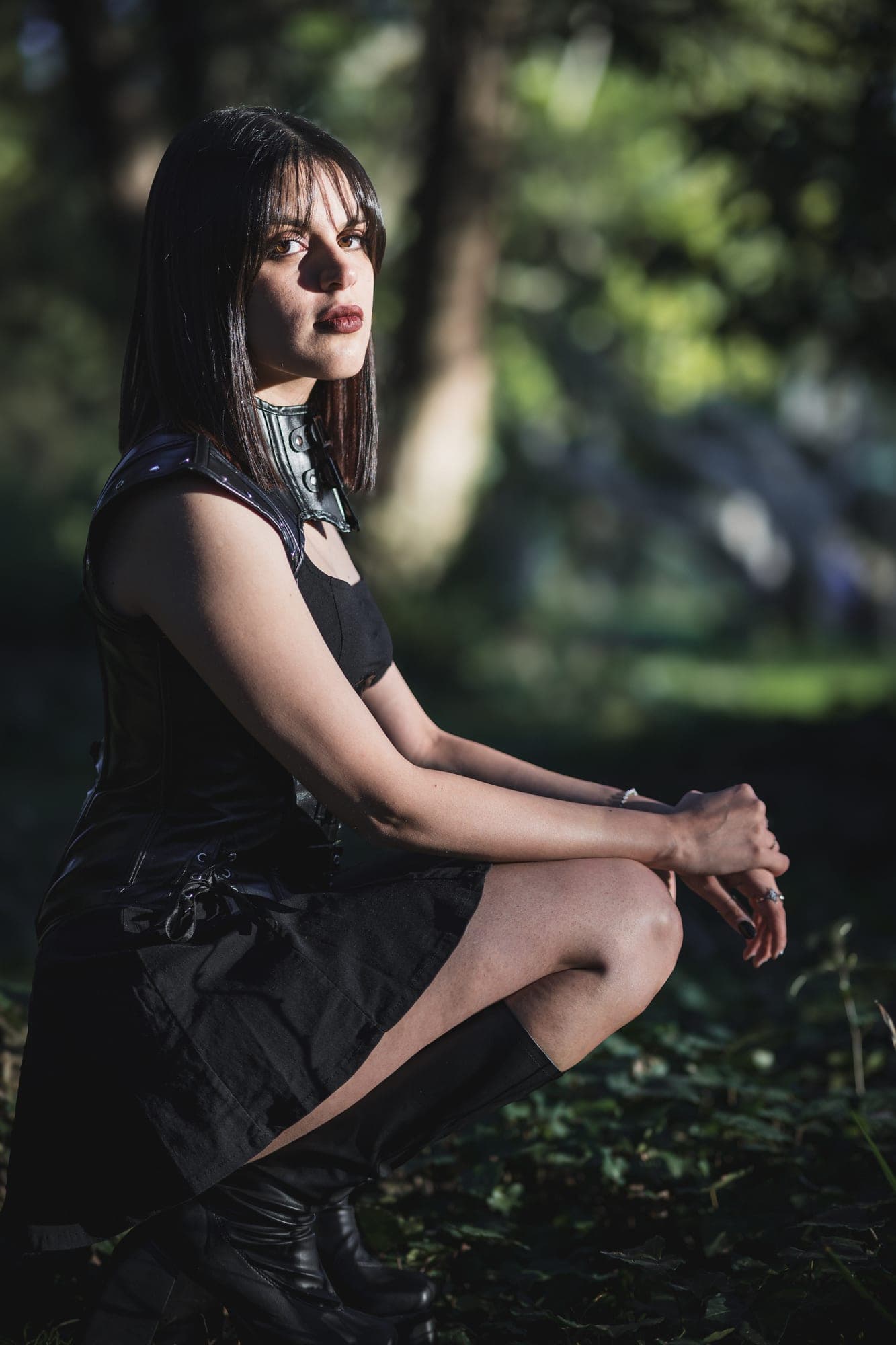 Retrato en cuclillas sobre el pasto, con luz de tarde entre los árboles